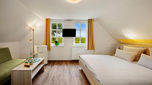 1 dormitorio con cama, sofá y ventana en Hotel Deichinsel en Wangerland