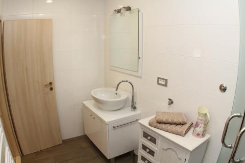 a white bathroom with a sink and a mirror at Studio Apartments Mirakul in Split
