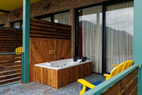a bath tub on a balcony with yellow chairs at Mtserlebi Resort in K'vishkhet'i