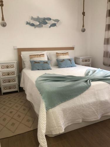 ein Schlafzimmer mit einem großen weißen Bett mit blauen Kissen in der Unterkunft Casa dos Pexins Buzina Sitio in Nazaré