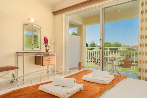 a room with two white chairs and a balcony at Manousis ApartHotel in Tsilivi