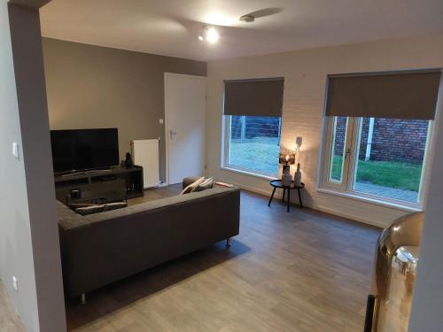 a living room with a couch and a flat screen tv at B&Bie Ons appartement in Bad-Nieuweschans