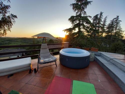 a hot tub on a patio with a chair and an umbrella at La Casa di Bacco B&B in Lerma