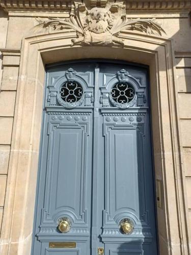 une porte bleue avec deux fenêtres sur un bâtiment dans l'établissement Charmant Studio lumineux calme Vue Panthéon Paris AC ascenseur, à Paris