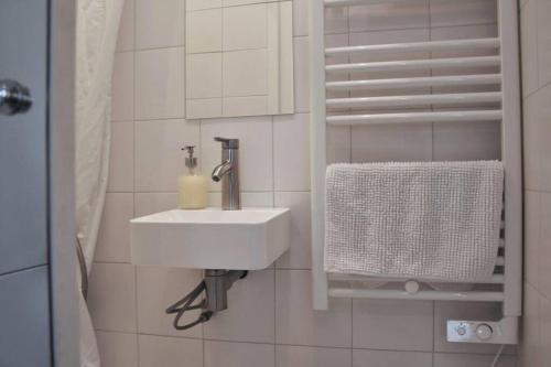 La salle de bains blanche est pourvue d'un lavabo et d'une serviette. dans l'établissement Charmant Studio lumineux calme Vue Panthéon Paris AC ascenseur, à Paris