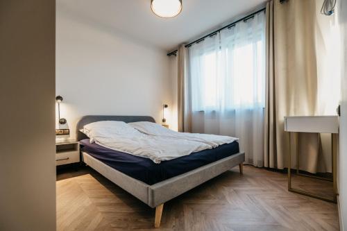 łóżko w pokoju z dużym oknem w obiekcie Nocosfera Apartament Premium Ogrodowy II w Kaliszu