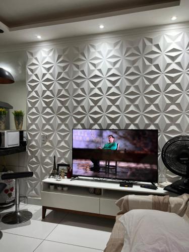 sala de estar con TV de pantalla plana grande en la pared en Apartamento cozzy, en Pipa