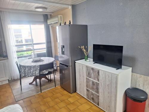 sala de estar con nevera y mesa con TV en Grand studio à 150m de la plage et 200m du port !, en Saint-Cyprien