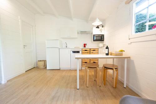 a white kitchen with a table and two stools at Bajo el Nogal in Camargo