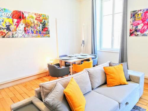 sala de estar con sofá gris y almohadas de color naranja en De 2 à 6 personnes - Le Street'Art - CROISÉE DES PARCS - A 20 minutes de Center Parc et Parc Animalier Sainte-Croix - Netflix - Wifi, en Sarrebourg