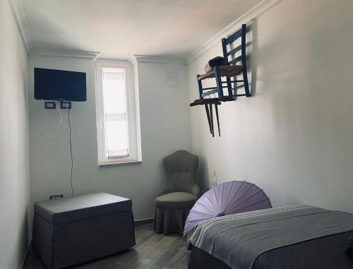 a bedroom with a bed and a chair and a television at L'appartamento di Rita in Nettuno