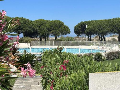 - une piscine avec des arbres et des fleurs au premier plan dans l'établissement Studio climatisé 4 couchages avec piscine et parking, accès direct plage - Port Camargue - FR-1-250-162, au Grau-du-Roi