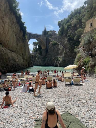 a group of people sitting on a beach near the water at Villa Pino in Furore