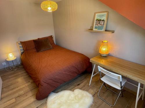 a bedroom with a bed and a desk with a lamp at La Petite Ardoise - Maison au calme pour 4 pers in Honfleur