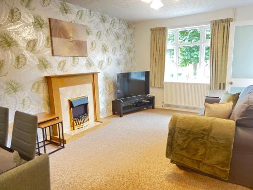 a living room with a fireplace and a television at Foxhill Bungalow in Glen Parva
