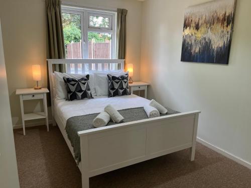 a bedroom with a white bed with pillows and a window at Foxhill Bungalow in Glen Parva
