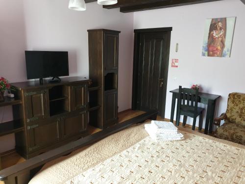 a living room with a bed and a tv at Casa Izvorul Rarăului in Câmpulung Moldovenesc
