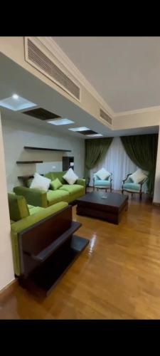 a living room with a green couch and a table at Golden in Mossadak Tower in Cairo