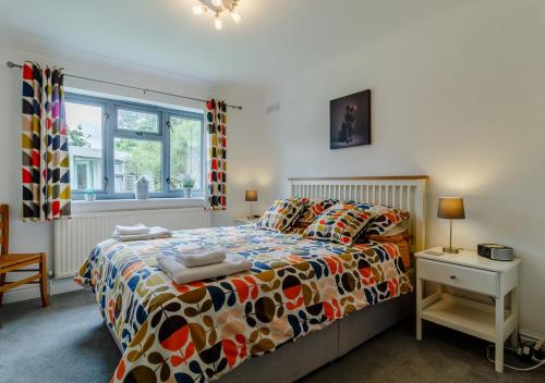 a bedroom with a bed with a colorful comforter and a window at Rushmere in Reydon