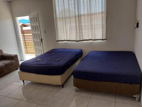 2 camas individuais num quarto com uma janela em Casa laranjal em Pelotas