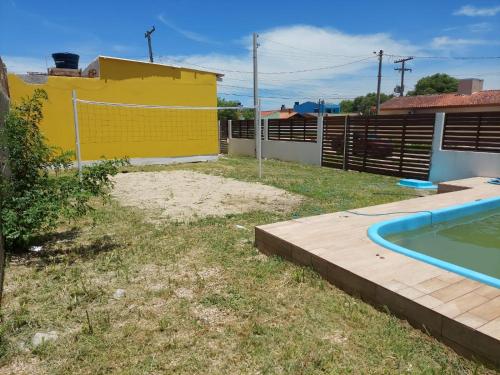 um quintal com uma piscina e uma casa amarela em Casa laranjal em Pelotas