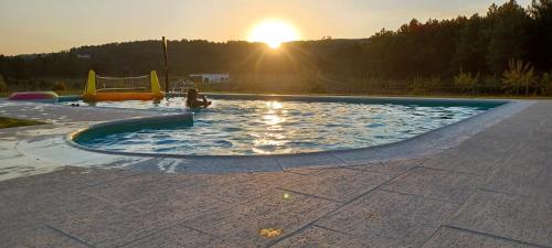 a child playing in a swimming pool with the sunset in the background at Quinta da Carreirinha in Vila Franca das Naves