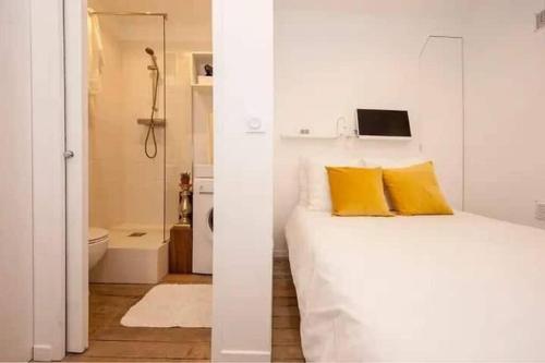 - une chambre blanche avec un lit et une salle de bains dans l'établissement Charmant studio rénové calme triangle d’Or Canal St Martin, à Paris