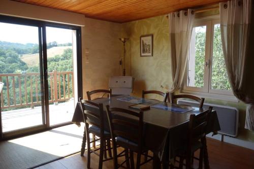 une salle à manger avec une table et des chaises et un balcon dans l'établissement Maison calme pès de Conques en Rouergue, à Sénergues