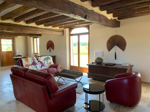 a living room with red leather furniture and an umbrella at Maison de charme en pleine nature in Saint-Germain-des-Grois