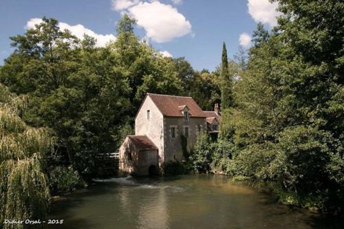 an old building sitting in the middle of a river at Maison de charme en pleine nature in Saint-Germain-des-Grois
