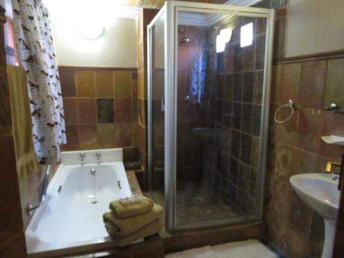 uma casa de banho com uma banheira, um chuveiro e um lavatório. em Harties Lodge - Rose Cottage em Hartbeespoort