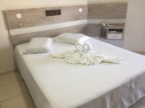 a large white bed with white sheets and pillows at Hotel AVM in Foz do Iguaçu