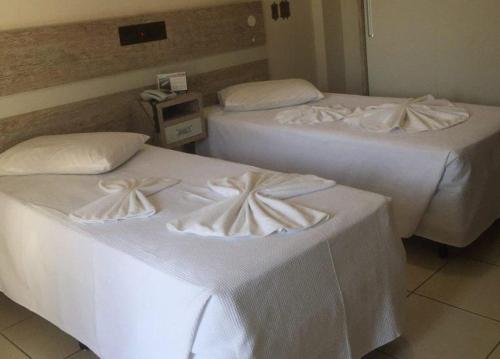 two beds in a hotel room with white sheets at Hotel AVM in Foz do Iguaçu