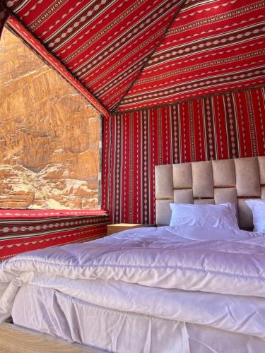 Cama en habitación con pared roja en Red Twilight Camp, en Disah