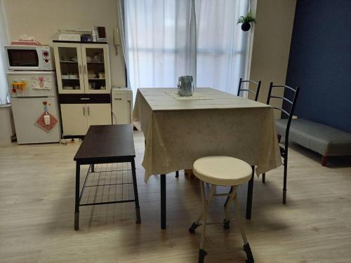 福岡的住宿－FukuokaKoryou GuestHouse，厨房配有带2把椅子的桌子和冰箱。