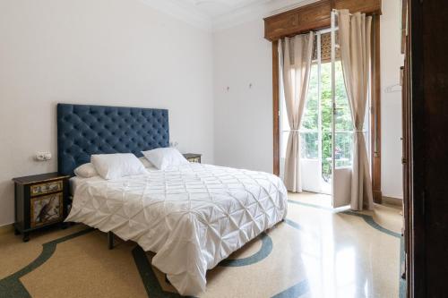 een slaapkamer met een bed met een blauw hoofdeinde en een raam bij Casa Bogart in Ourense