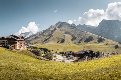 Appartement Manigod/La clusaz في مانيجود: منزل على تل مع جبل في الخلفية