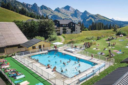 a large swimming pool with people in it with mountains at Appartement Manigod/La clusaz in Manigod