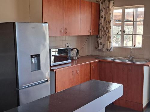 a kitchen with wooden cabinets and a stainless steel refrigerator at KASP Cottage in Underberg