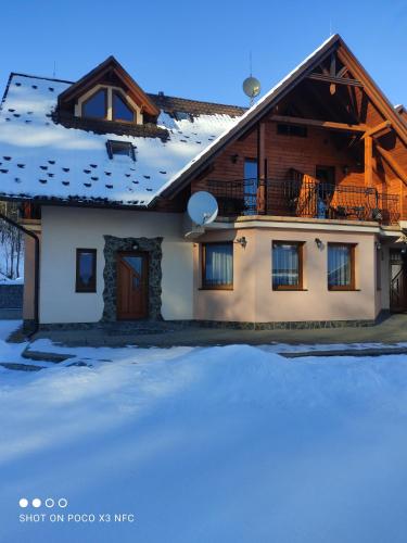 a house with snow on the ground in front of it at Penzión ORCHIDEA in Vitanová