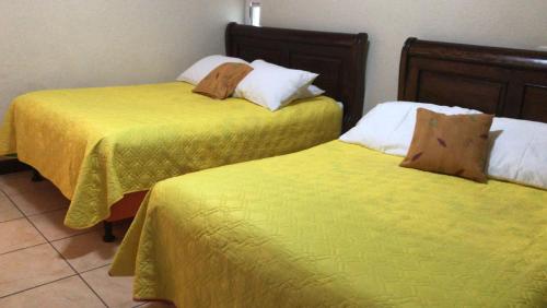 two beds in a hotel room with yellow sheets at Hotel Hawaian Paradise in Hawaii