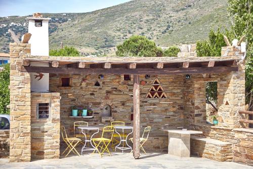 a stone building with yellow chairs and a table at Irene Studios in ayios Petros