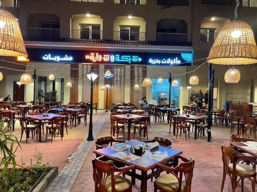 un restaurant vide avec des tables, des chaises et des lumières dans l'établissement قريه اكوا فيو الساحل الشمالى-Aqua View North Coast, à El Qasaba esh Sharqīya