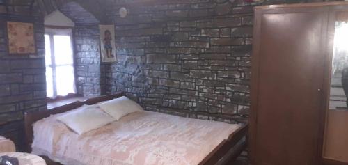 a bed in a room with a brick wall at guest house in buhal in Përmet