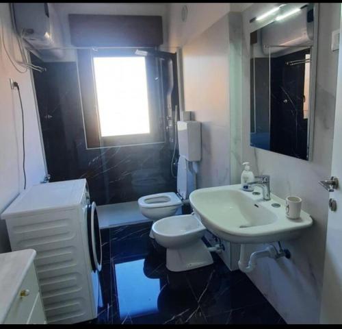 a bathroom with a sink and a toilet and a window at Verdisuite - Trento centro - Parcheggio privato gratuito in Trento