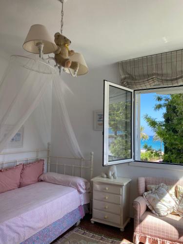 a bedroom with a bed and a couch and a window at La Digue Beach House in San Vicente de Calders