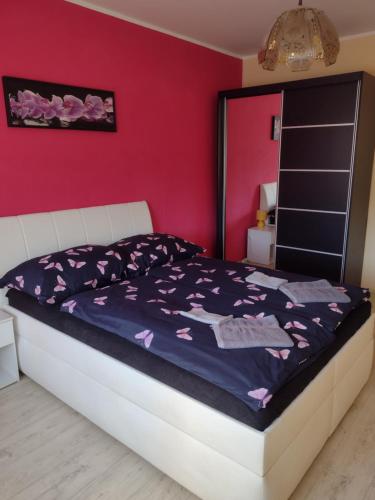 a bed in a bedroom with a red wall at Apartmens KV in Karlovy Vary