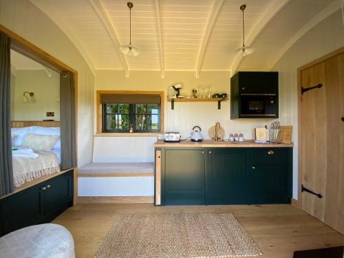 - une cuisine avec évier et un lit dans une chambre dans l'établissement The Rabbit Warren Shepherd Hut, à Ketton