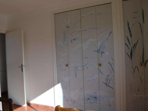 un placard blanc avec des oiseaux peints sur le mur dans l'établissement Maison Familiale 4 Pièces, 6 Couchages, Près de la Plage à Saint Pierre la Mer - FR-1-229D-76, à Fleury