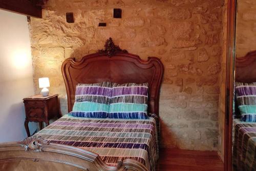 - une chambre avec un lit en bois dans un mur en pierre dans l'établissement Duplex avec cour au coeur de la cité médiévale., à Gourdon